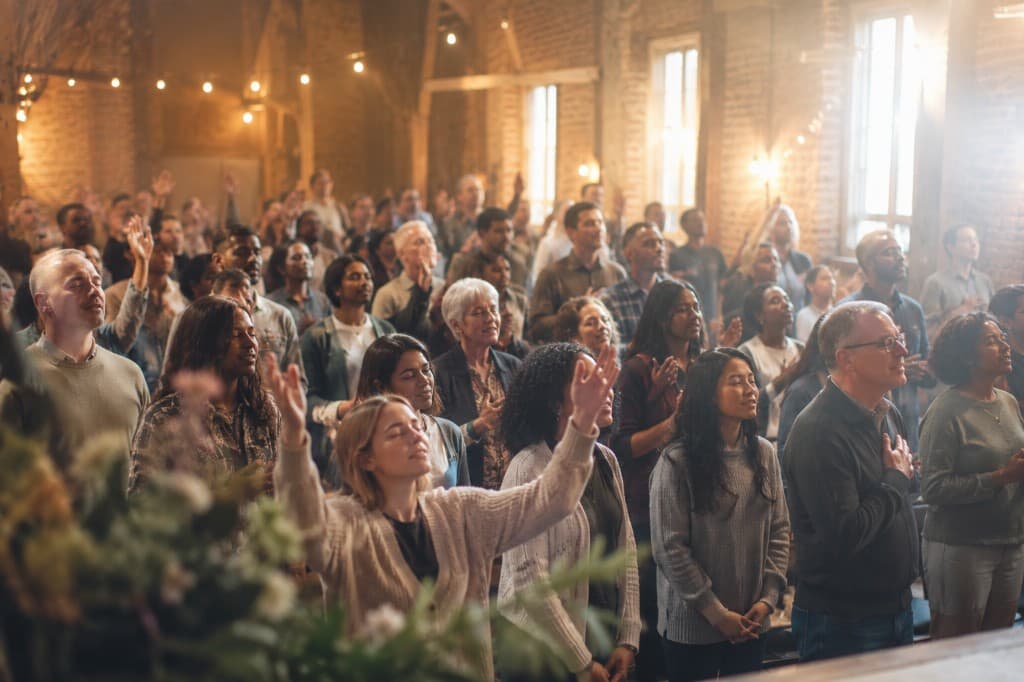 A congregation worshipping together on a Sunday morning, hands raised in a warmly lit mosque